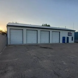 A large white building with a lot of garage doors and a blue door.