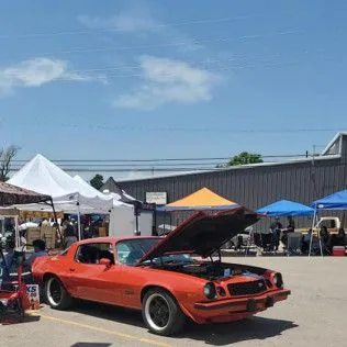 Orange Chevrolet Camaro with its hood up at an outdoor car show