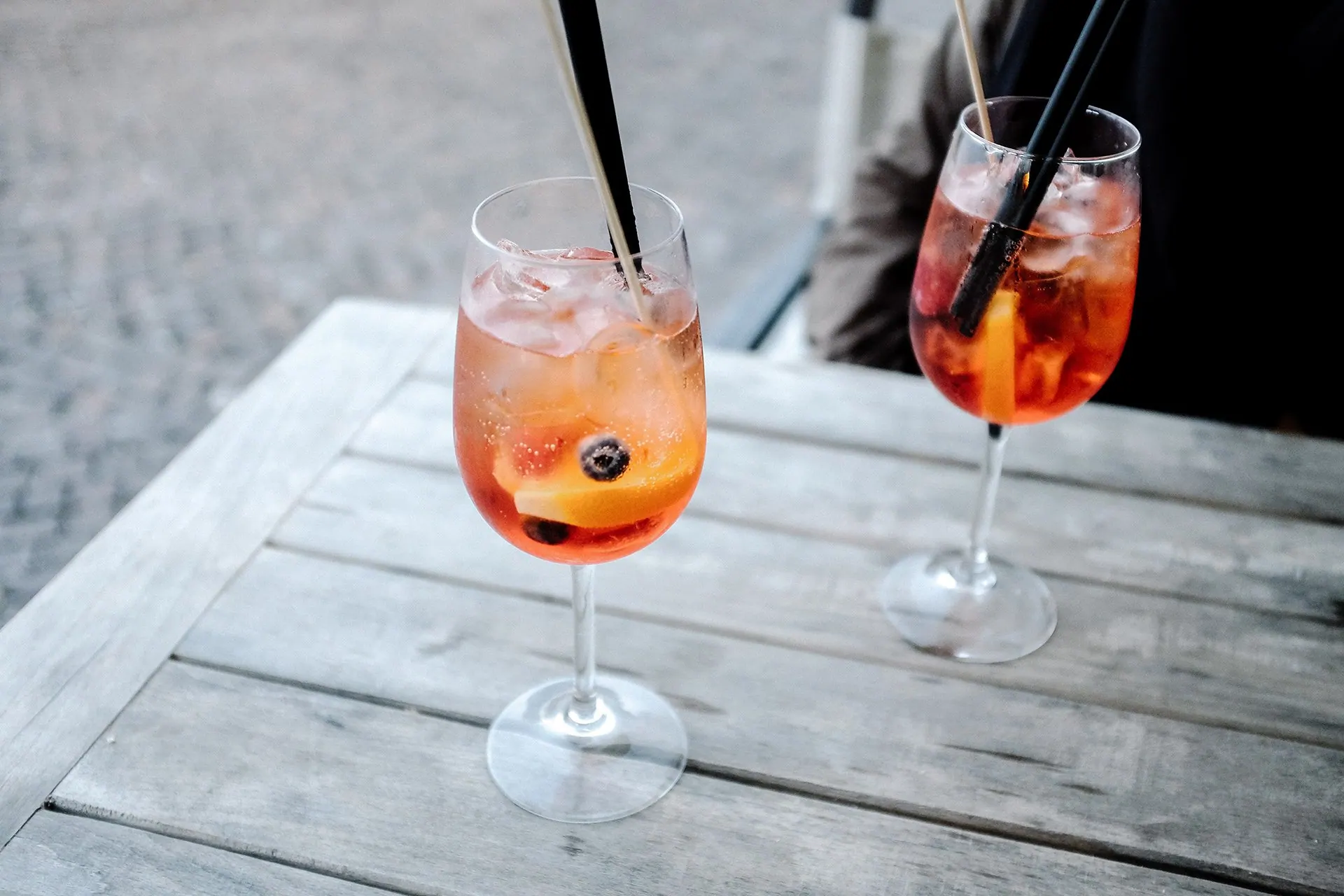 Two iced spritz cocktails on a wooden café table