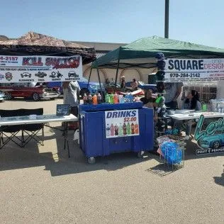 A vendor is selling drinks at a car show.